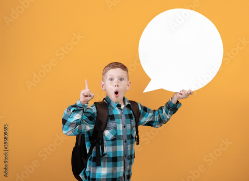 Excited boy with backpack thinking on yellow background