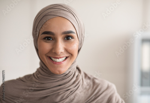 Portrait of cheerful woman in hijab over clinic interior