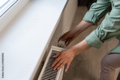 Closeup of a radiator thermostat with woman hand