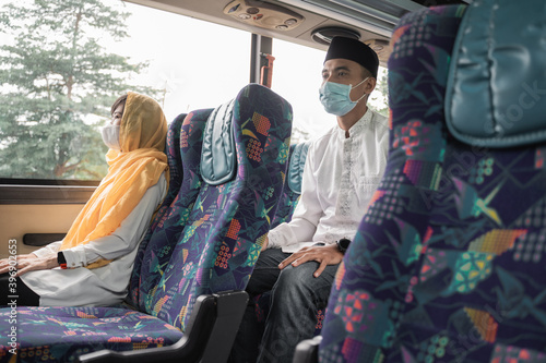 muslim couple wearing masks and travel by bus during eid mubarak holiday to meet family at home