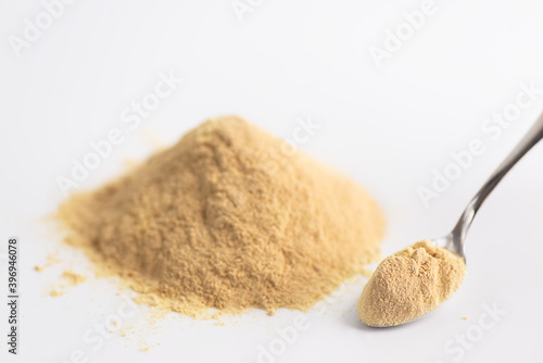 Sunflower lecithin heap with a spoon on a light background.