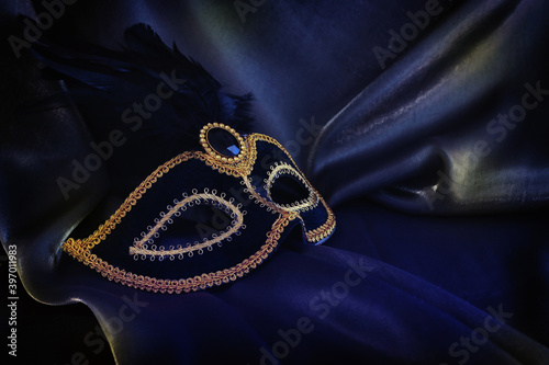 Photo of elegant and delicate Venetian mask over dark silk background