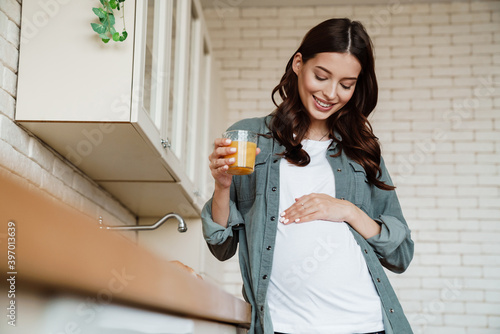 Happy charming pregnant woman smiling and drinking juice