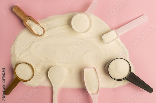 Frame made with protein powder and pills spoons on pink background. Extra protein intake. Natural beauty and health supplement for skin, bones, joints and gut. Plant or fish based. Flatlay, top view.
