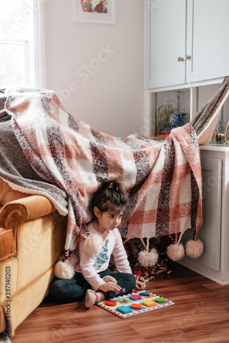 Child playing in front of blanket fort at home