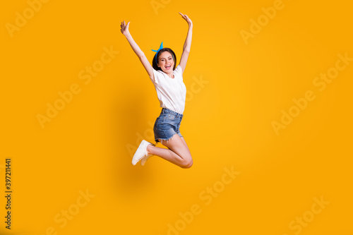 Full length body size photo of cheerful young woman jumping high smiling keeping hands over head isolated on vivid yellow color background