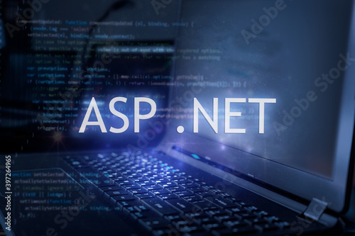 ASP .NET inscription against laptop and code background. Learn dot net programming language, computer courses, training.