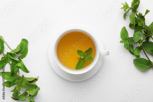 Cup of tasty mint tea on white background