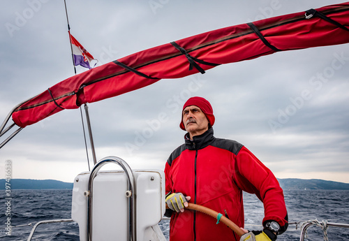 An experienced skipper steers the yacht peering into the distance