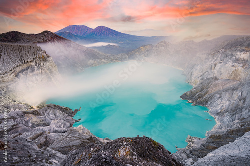 View from above, stunning aerial view of the Kawah Ijen volcano complex at sunset with the blue acid lake and some clouds of toxic gases raising from a sulfur deposit. East Java, Indonesia.