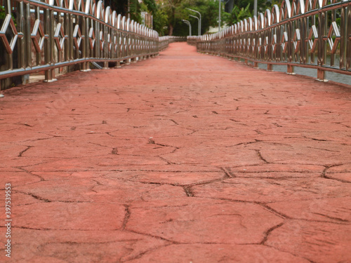 Scene of bridge. Road view. Red brown stylish, stone texture of road receding into the distance. Long bridge and metal railings. View from the beginning to the end. Roadbed -  macro, close up view. 