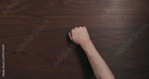 Top view man hand knock on black walnut table with copy space