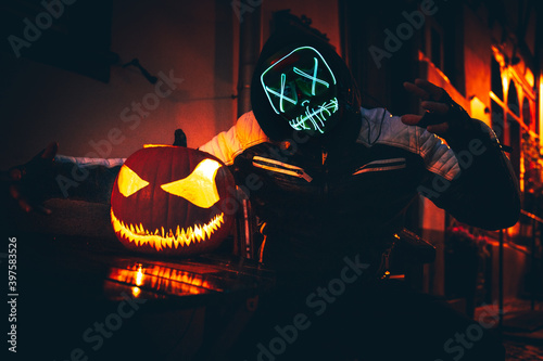 Purge mask, halloween with pumpkin. LED mask, creepy scary man. Corona, Funny, October, outside. Urban scene