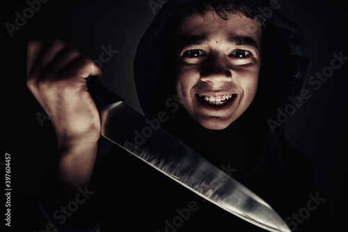 Boy in hoodie with knife in hand. Violent boy. Juvenile delinquent concept