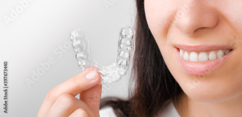 Close up woman holding a transparent removable braces for perfect smile. Orthodontic aligners for straightening and whitening teeth.