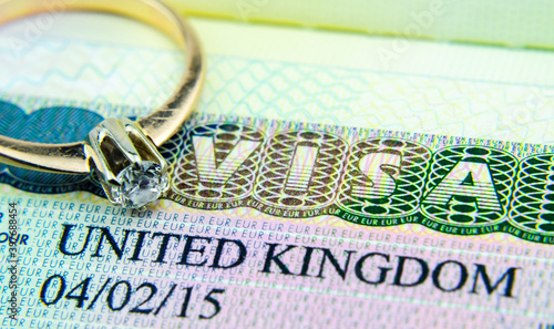UK entry visa sticker in a passport and the engagement ring placed on top. Conceptual photo for fiance / spouse visa and immigration in general.