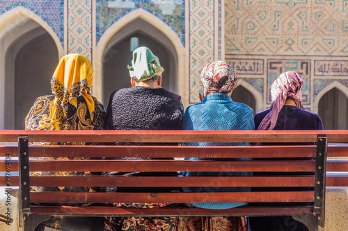 BUKHARA, UZBEKISTAN - MAY 1, 2018: Local women sit on a bench at the Kalyan Mosque in Bukhara, Uzbekistan