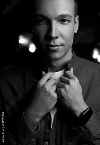 Beautiful young guy on a black blurred background, balck and white