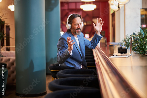 Delighted man enjoying listening to his playlist at hotel lounge