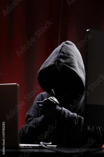 International hacker in black pullover and black mask trying to hack government on a black and red background. Cyber crime . Cyber security.
