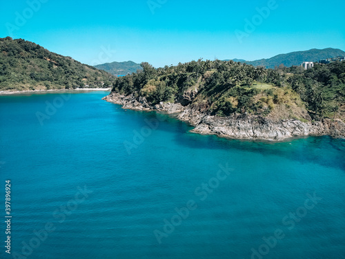 Top view of the beautiful coast of an isolated island around which clear blue water with inspiring waves