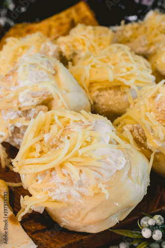 A row of delicious cheesy Ensaymada at a buffet table. It a Filipino sweet dough pastry covered with butter and sugar then topped with lots of cheese.