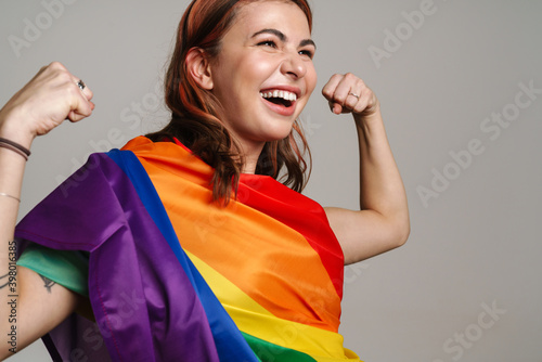 Cheerful woman wearing rainbow flag laughing and showing her biceps