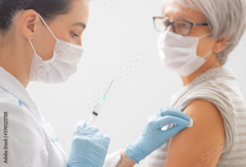 Doctor giving a senior woman a vaccination