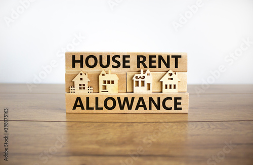 House Rent Allowance symbol. Wooden blocks with words 'House Rent Allowance', miniature houses. Beautiful wooden table, white background, copy space. Business and House Rent Allowance concept.