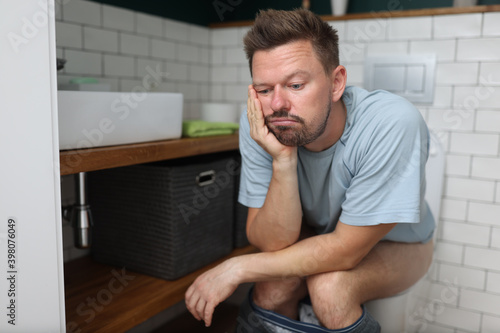 Man sit on toilet with constipation and wait for laxative to take effect. Digestive system disease and treatment.