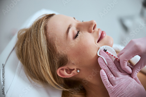 Experienced cosmetologist reducing the patient nasolabial folds