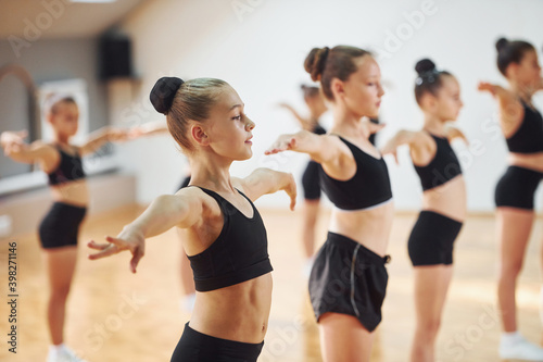 Side view of group of female kids that practicing athletic exercises together indoors