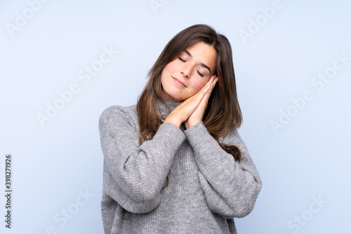 Teenager Brazilian girl over isolated blue background making sleep gesture in dorable expression