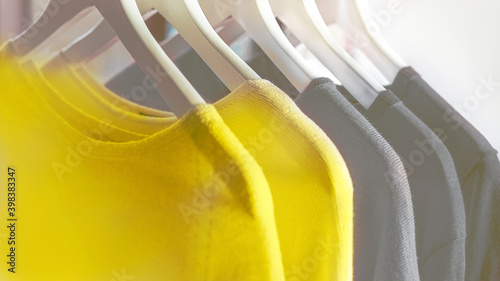 Bright illuminating yellow and gray colours clothes on hangers.