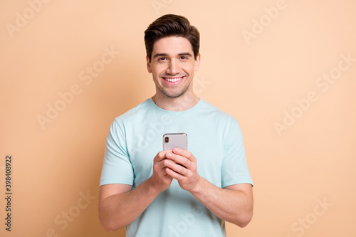 Portrait of nice cheerful guy influenzer blogger using gadget app 5g post media isolated over beige pastel color background
