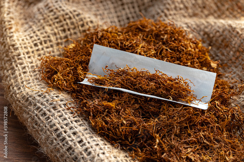 Cigarette paper and pile of tobacco on wooden table