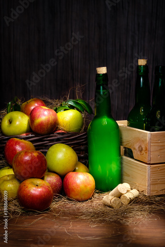 Asturian cider bottles many red and green apples at basket over wooden background