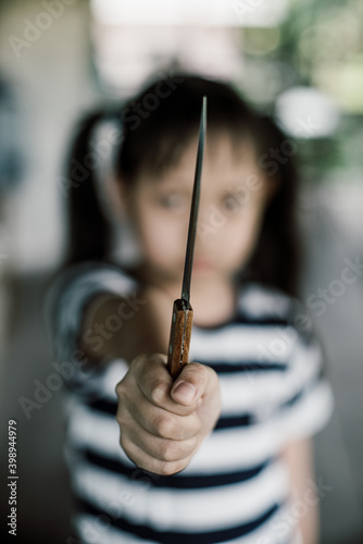 Angry little child girl with a knife in her hand