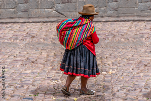Peru, woman in her colourful traditional dress is walking in the street.