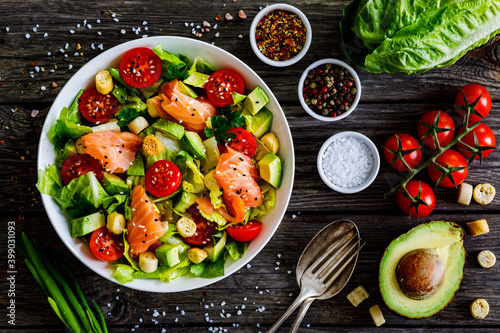Salmon salad - smoked salmon with avocado and mix of vegetables on wooden table