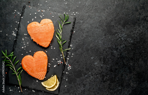 Two raw salmon fillets with heart shaped spices on a stone background with copy space for your text
