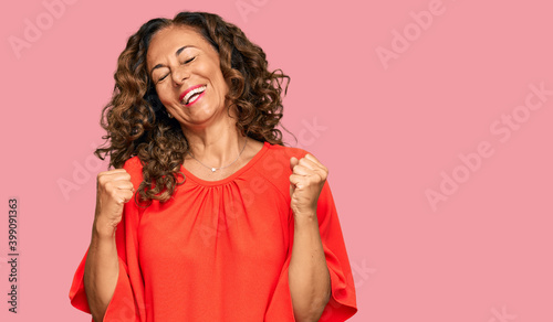 Middle age hispanic woman wearing casual clothes very happy and excited doing winner gesture with arms raised, smiling and screaming for success. celebration concept.