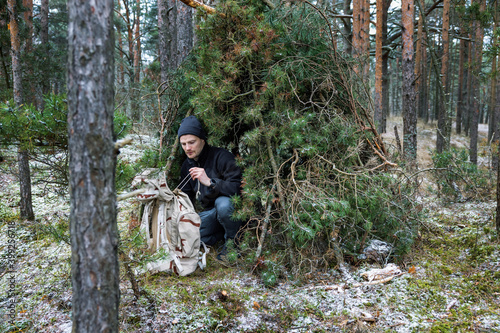 outdoor adventure - man in tree branch shelter into the wild