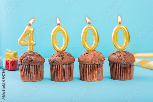 4000 Number gold candle on a cupcake against a pastel blue background four thousand year celebration