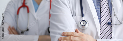 Man and woman doctors with phonendoscope around their necks stand with hands folded closeup. Work in private medical centers concept.