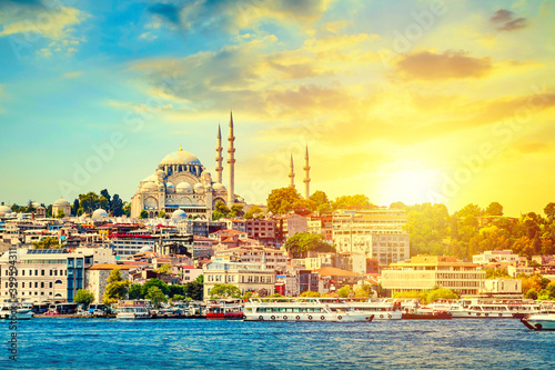 Touristic sightseeing ships in Golden Horn bay of Istanbul and view on Suleymaniye mosque with Sultanahmet district against beatiful sunset.