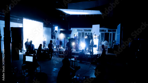 Silhouette images of video production behind the scenes or b-roll or making of TV commercial movies that film crew team lightman and videos cameraman working together with movie director in studio.