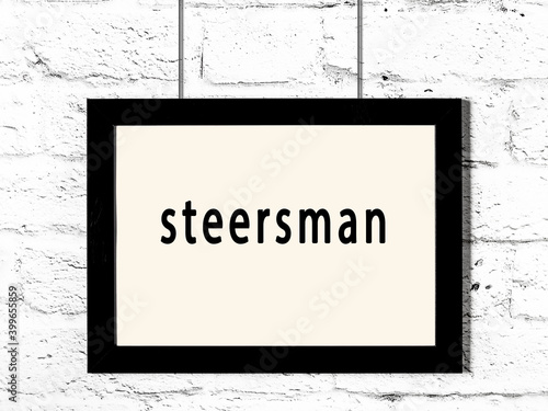 Black frame hanging on white brick wall with inscription steersman