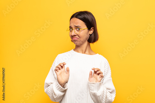 young latin woman feeling disgusted and nauseous, backing away from something nasty, smelly or stinky, saying yuck