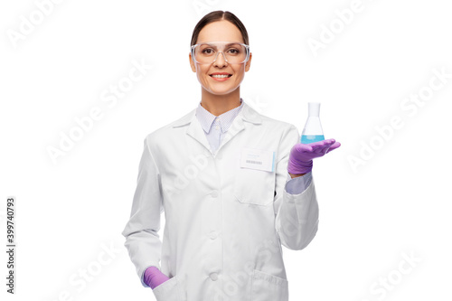 science, chemistry and people concept - happy smiling young female scientist in goggles with chemical in flask making test or research